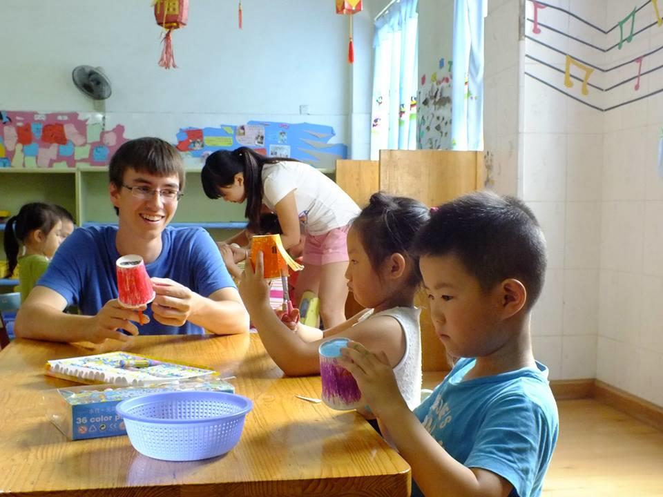 Projects Abroad male volunteer helps with arts and crafts at a day care centre during his Childcare project in China. Projects Abroad volunteers working with children in China participate in an arts and crafts activity at a care centre.